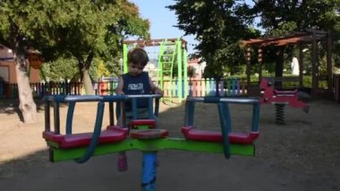 Yakışıklı küçük çocuk oyun alanında eğleniyor. 