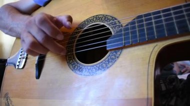 Ahşap akustik gitarda çalan adam.