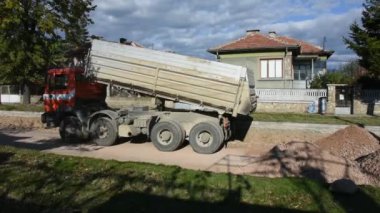 Yol asfaltlaması için taş taşıyan büyük bir inşaat kamyonu.