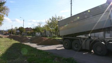 Yol asfaltlaması için taş taşıyan büyük bir inşaat kamyonu.