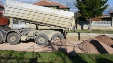 Yol asfaltlaması için taş taşıyan büyük bir inşaat kamyonu.