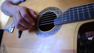 Ahşap akustik gitarda çalan adam.