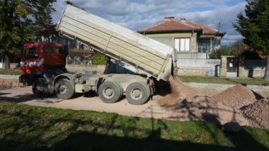Yol asfaltlaması için taş taşıyan büyük bir inşaat kamyonu.