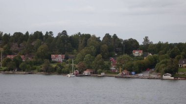 houses on island at river, trees and summer nature around 