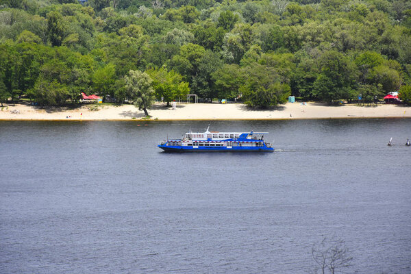 travel touristic bout on river Dnipro in Kyiv, green summer park trees on island 