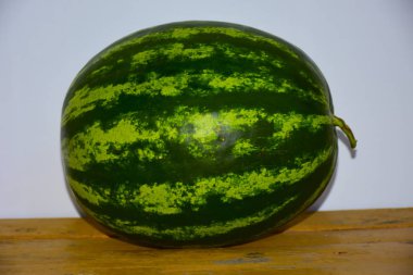 Ahşap masada olgun karpuz resmi.