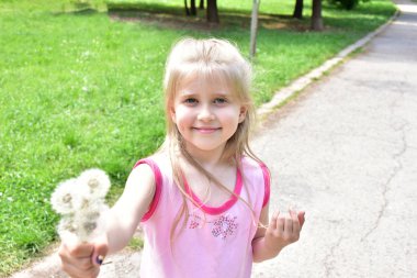 Elinde karahindibalar olan küçük bir kız.,