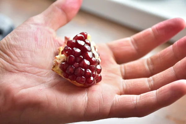 red pomegranate grains on hand,