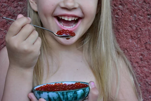 子供は魚から赤いキャビアを食べます — ストック写真