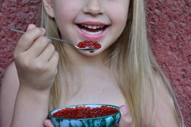 Çocuk balıktan kırmızı havyar yiyor.,