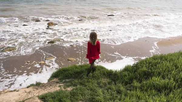 Joyeux jeune femme en robe rouge amusez-vous à la falaise de la côte de la mer — Photo