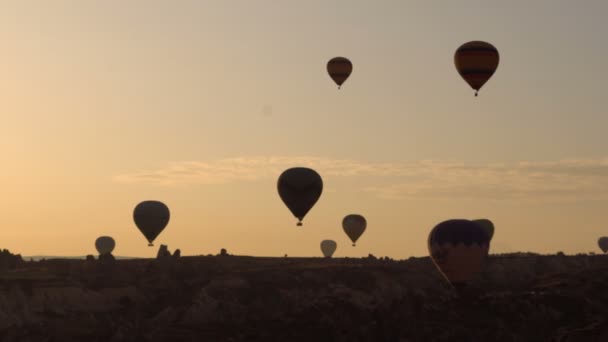 Silhuetter massor av Luftballonger som flyger över dalar i Göreme, Turkey. Turister från hela världen kommer till Cappadocia göra en resa i en hot-air ballonger. — Stockvideo