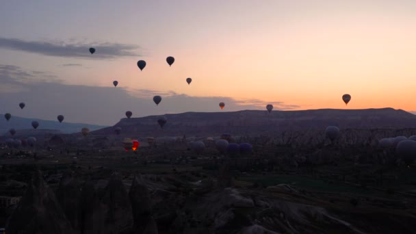 Siluetas Muchos globos aerostáticos volando sobre valles en Goreme, Turquía. Turistas de todo el mundo vienen a Capadocia para hacer un viaje en globos aerostáticos . — Vídeos de Stock