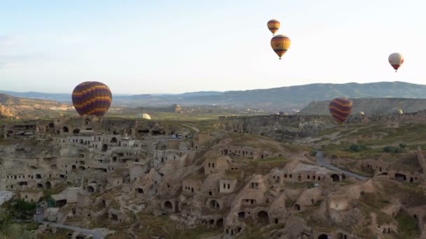 Muitos balões de ar quente voando sobre vales em Goreme, Turquia Voando sobre a antiga cidade da caverna em Rose Valley . — Vídeo de Stock