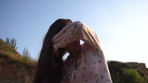 Retrato de adorable caucásico morena chica en luz rosa vestido jugar con su largo hermoso cabello a la salida del sol . — Vídeo de stock