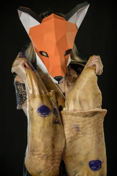 Chica rubia con papel de máscara de zorro usando piel de cerdo para cubrir. Consumidor animal muerto — Foto de Stock
