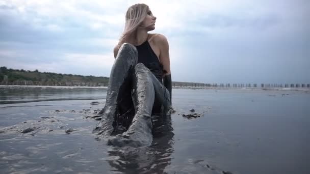Очаровательная стройная блондинка, размазанная черной грязью, похожа на нефтяное масло — стоковое видео