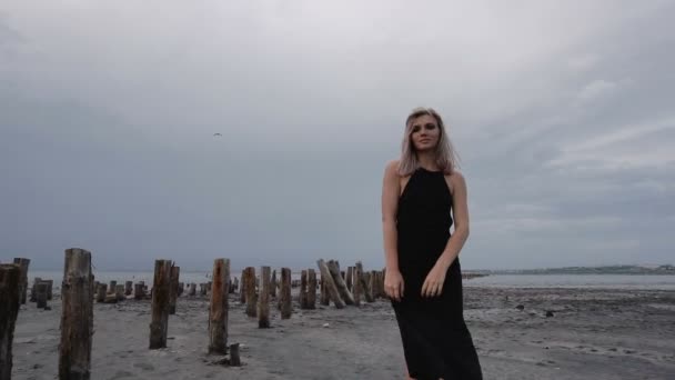 Adorable rubia delgada en la costa de Firth Sal con barro negro saludable con estacas de madera que sobresalen de la tierra . — Vídeos de Stock