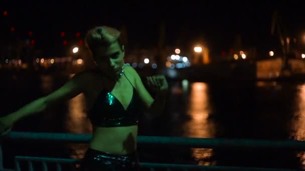 Street punk or hipster girl with pink dyed hair. Woman with piercing in nose, lenses, ears tunnels and unusual hairstyle stands at night illuminated city. — Stock Video
