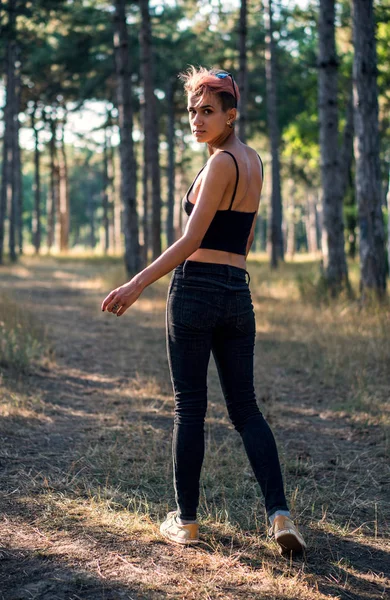 Jovem Bonita Punk Girl em Pano Negro com Cabelo Rosa na Floresta de Pinheiro ao Pôr do Sol — Fotografia de Stock