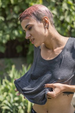 Genç oldukça deldi kız Bahçe hortum duş sonra ıslak tişörtlü. Yaz eğlence ve ıslak tişört.