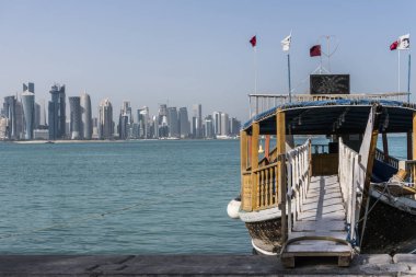 Geleneksel ahşap tekne Broadway'de Corniche merdivenden Körfez şehir turizm tur için davet ediyoruz. Yüzen Katar bayraklı güzel Doha manzarası görünümü ile. Katar, Orta Doğu