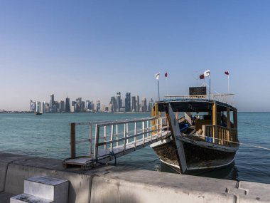 Geleneksel ahşap tekne Broadway'de Corniche merdivenden Körfez şehir turizm tur için davet ediyoruz. Yüzen Katar bayraklı güzel Doha manzarası görünümü ile. Katar, Orta Doğu