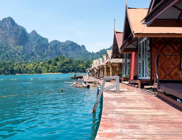 Floating wooden houses on a lake with mountains and rain forest in the background during a sunny day at Ratchaprapha Dam at Khao Sok National Park, Thailand — Stock Photo, Image