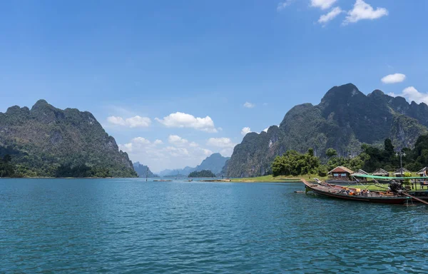 Wooden Thai traditional long-tail boat on a lake with mountains and rain forest in the background during a sunny day at Ratchaprapha Dam at Khao Sok National Park, Thailand — Stock Photo, Image