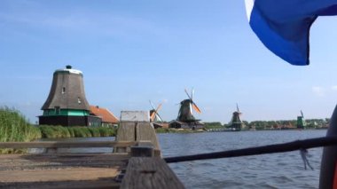 Geleneksel Hollanda yel değirmenleri Zaanse Schans'a, Hollanda bir ön plan üzerinde bayrak. Turistik köyü yakınında yel değirmenleri ile Amsterdam ve tarihi Hollanda evleri