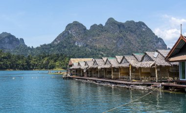 Ahşap Tay geleneksel yüzen evler dağlar ve yağmur ormanı Ratchaprapha Barajı Khao Sok Milli Parkı, Tayland, Thailand, güneşli bir gün sırasında arka planda bir gölde
