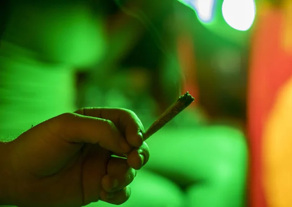 Hand with a marihuana weed in joint cigarette on green background — Stock Photo, Image