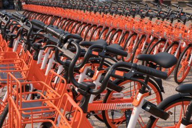 Satır genel kullanım için turuncu bisiklet sokakta park edilmiş.