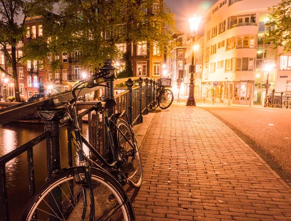 Nederländerna, Amsterdam - 23 Aug 2018: natt över staden Amsterdam. Cyklar på en kanal bro och typiska holländska hus, Holland, Nederländerna. — Stockfoto