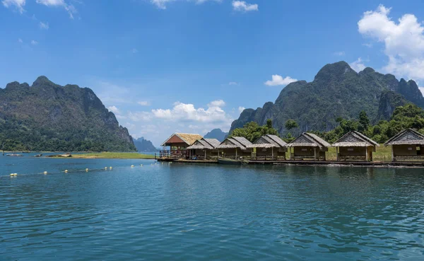 Wooden Thai traditional floating houses on a lake with mountains and rain forest in the background during a sunny day at Ratchaprapha Dam at Khao Sok National Park, Thailand — Stock Photo, Image