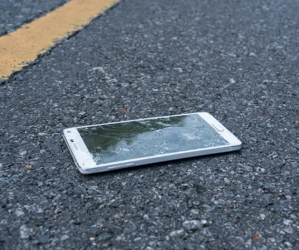 Yeni beyaz Smartphone asfalt yolda kırık. Birisi düştü aygıt. Büyük bir ekran üzerinde çatlaklar