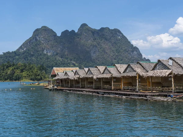 Wooden Thai traditional floating houses on a lake with mountains and rain forest in the background during a sunny day at Ratchaprapha Dam at Khao Sok National Park, Thailand — Stock Photo, Image