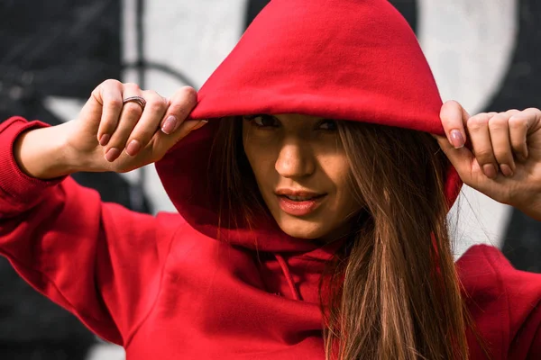 Närbild porträtt av bedårande kaukasiska flicka i kostym för sport. Vackra unga fit fitness sport modell i röd Huvtröja nära målade väggen. — Stockfoto