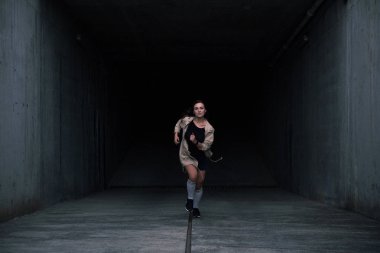 Yaşam tarzı görüntü karanlık beton koridor gülümseyen dışında çalışan bir genç çok kestane rengi saçlı beyaz kız. Hoş rahat elbise.