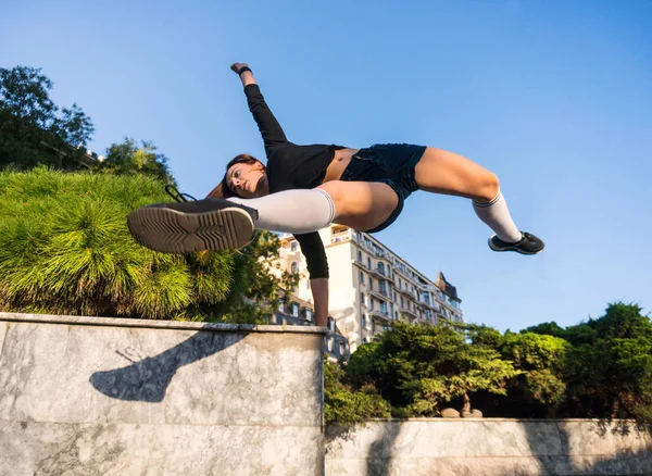 Outdoor lifestyle image of a young pretty chestnut haired caucasian girl having fun and striking a gymnastic pose on the street. Cute casual outfit — Stock Photo, Image