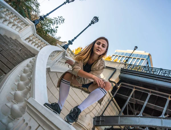 Utomhus hösten livsstil bild av en ung ganska kastanj haired kaukasiska flicka ha roligt och dansa på gatan på trappan. Söt casual outfit framför byggnaden. — Stockfoto