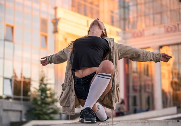 Lebensstil im Freien Bild eines jungen hübschen kastanienhaarigen kaukasischen Mädchens, das auf der Straße tanzt. Nettes Freizeitoutfit vor gläsernem Gebäude. — Stockfoto