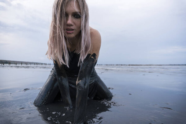 Portrait of Blonde Caucasian Girl Crawls Smeared in a Healthy Black Mud in old Firth