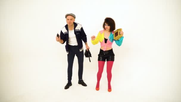 An old fashioned young man and a girl dancing. Girl is holding a boombox, man has got a purse and a phone in his hands — Stock Video