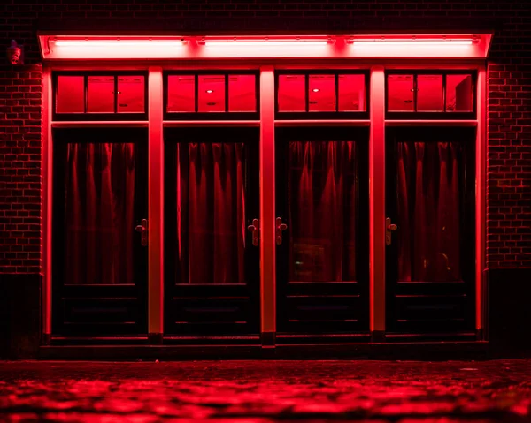 Rotlichtviertel in Amsterdam. Rote Boxen mit Vorhängen und nassem Kopfsteinpflaster auf der Straße — Stockfoto