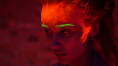 Güzel bir genç seksi kız yüz ve saç siyah ışık konuşmaktan parlak boya ile. Siyah lamba ışığında parlayan bodyart güzel kadınla.