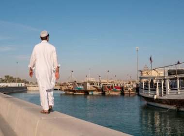 Orta Doğu insan Corniche road, Doha tarafından yürüme. Görünüm katar bayrakları yüzen ile geleneksel ahşap tekneler ile. Corniche Broadway. Katar, Orta Doğu