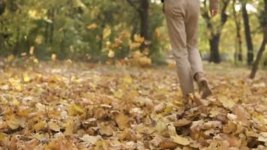 Sarı akçaağaç yığınları genç streetstyle casual adam sonbahar park ve tekme yürüyüş güneş gözlüğü çıkar