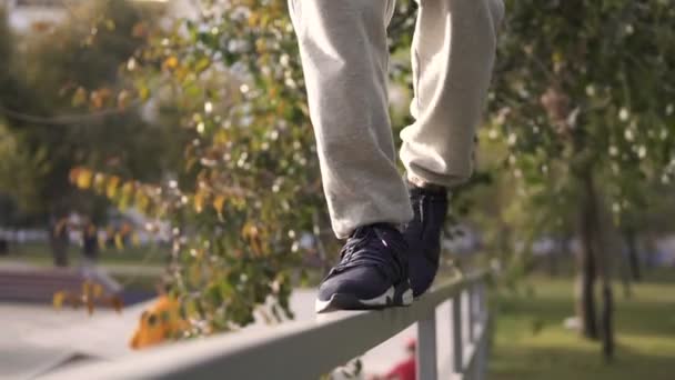 Hombre joven callejero caminar por barandilla en la frontera de skatepark en la ciudad de otoño . — Vídeos de Stock