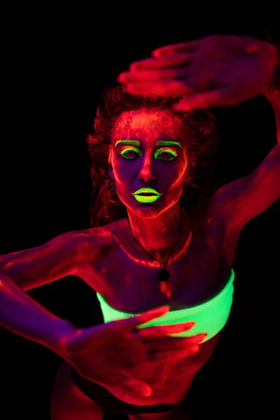 Ritratto di una bella giovane ragazza sexy con vernice ultravioletta sul suo corpo. Bella donna con bodyart incandescente in luce lampada nera — Foto Stock